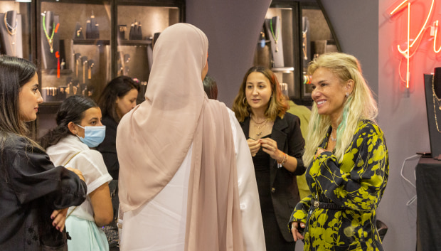 A woman in a hijab engages in conversation with a group of women, fostering connection and dialogue among them.