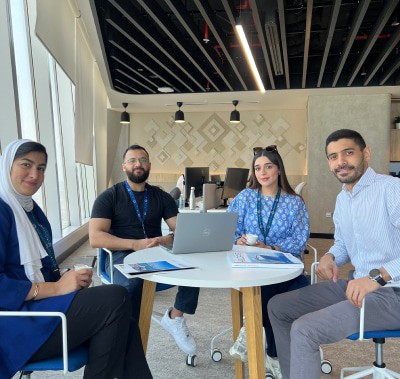 A group of four people gathered around a table collaborating on a project.