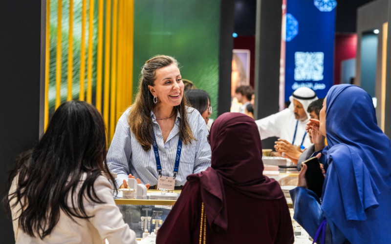 Jewellery exhibition booth with representative speaking to visitors at a trade show.