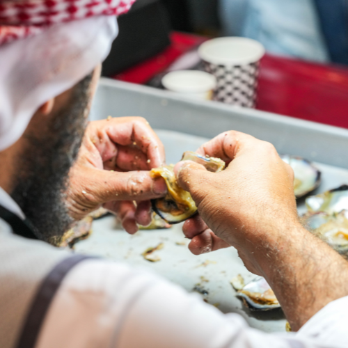 Jeweller opening an oyster to reveal a pearl during a demonstration.